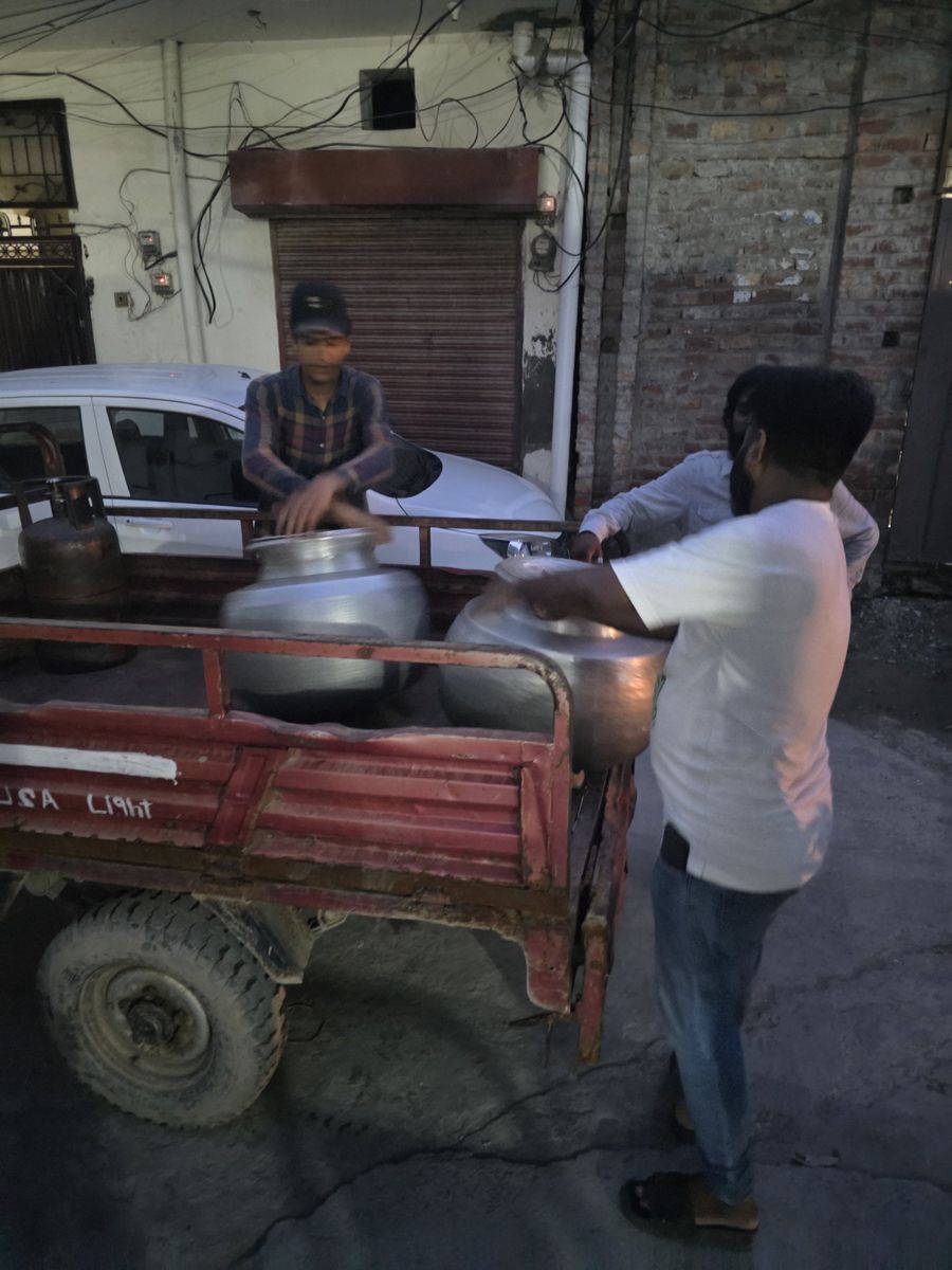 Volunteers loading large cooking pots onto a rickshaw