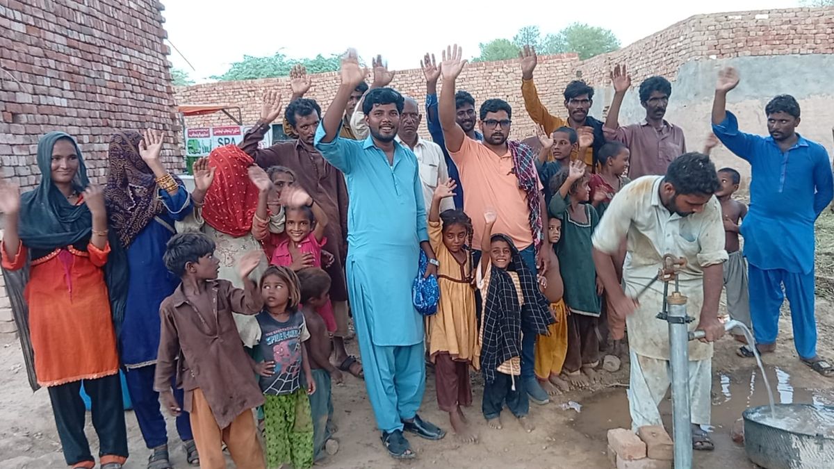 Villagers waving next to a newly installed hand pump